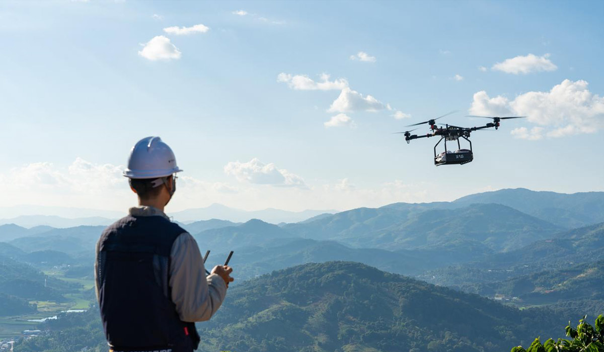a man operate a 4 Rotor drone moving sand in bags